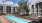 Lap pool with lounge seating on the pool deck and enclosed hammock courtyard with large oak tree.