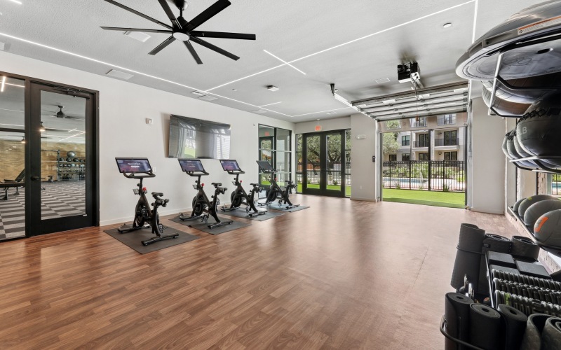 Cardio room with equipment and garage door to outdoor workout lawn