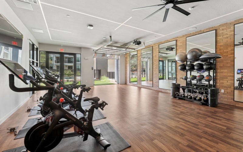 Cardio room with equipment and garage door to outdoor workout lawn